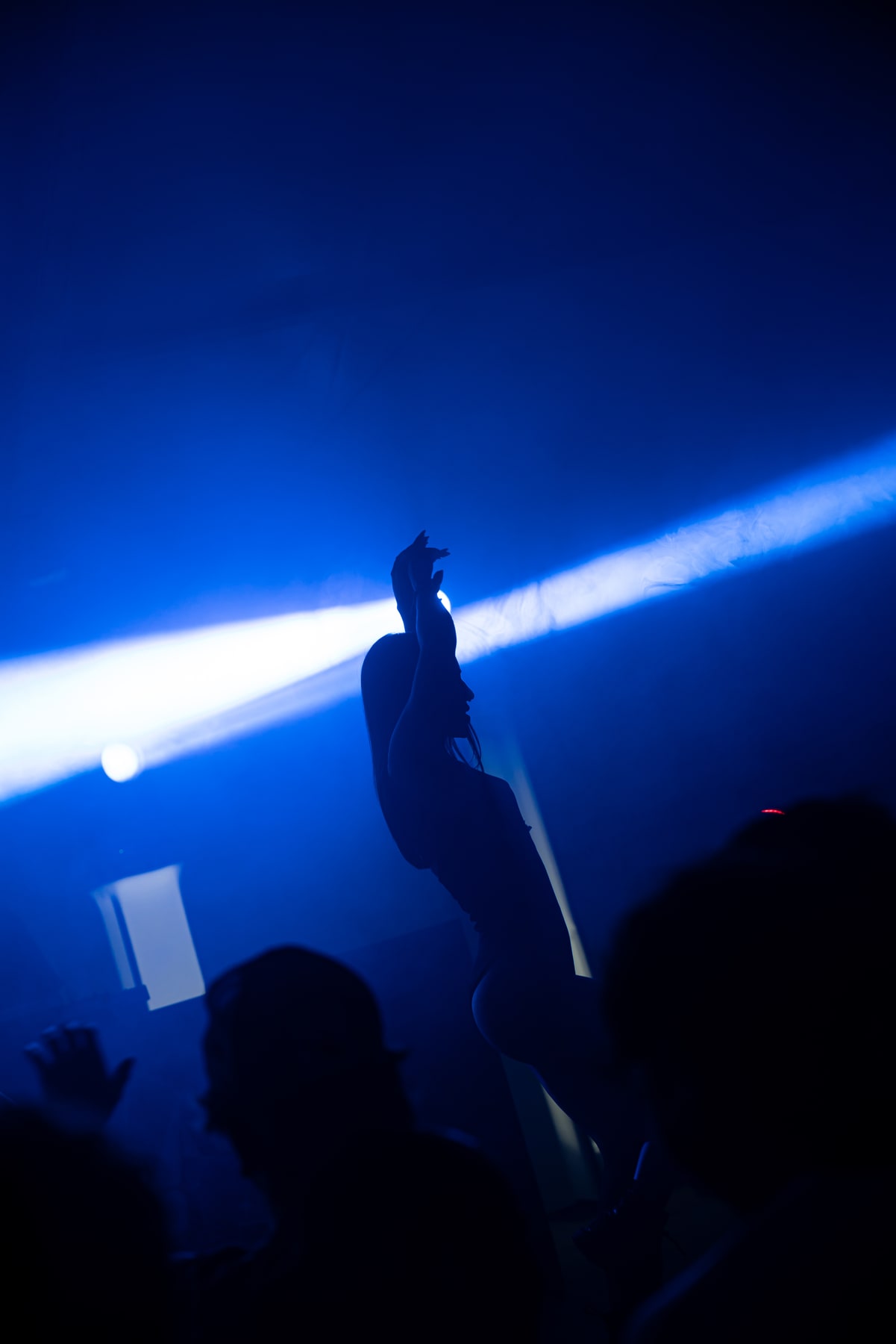 Un artista in silhouette tra i fasci di luce blu sul palco.